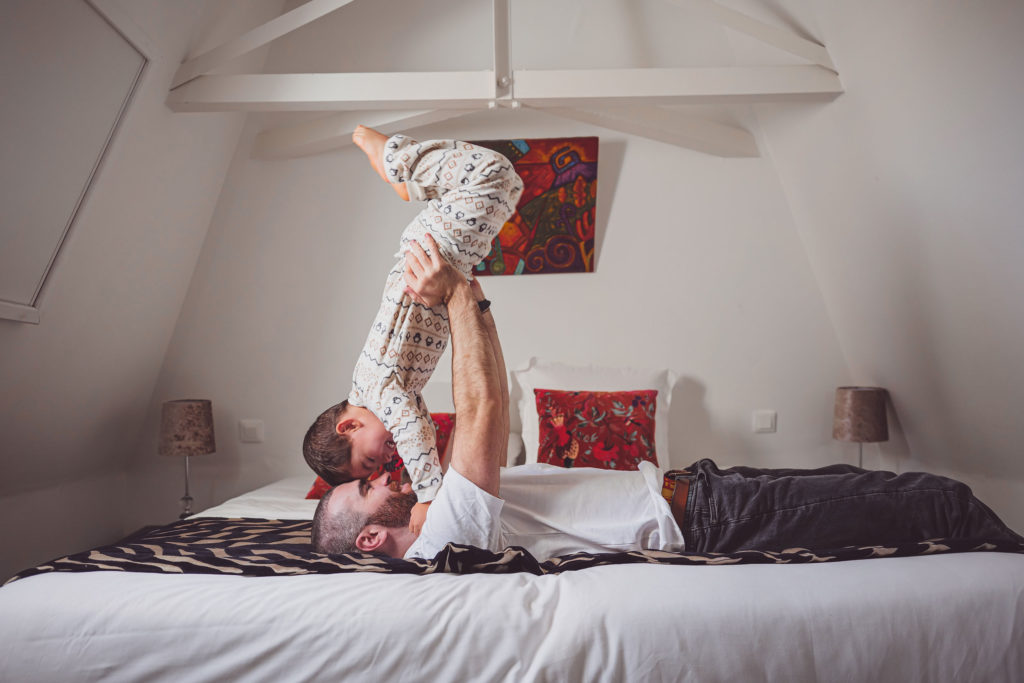 Papa avec son enfants qui s'amuse sur le lit de la chambre