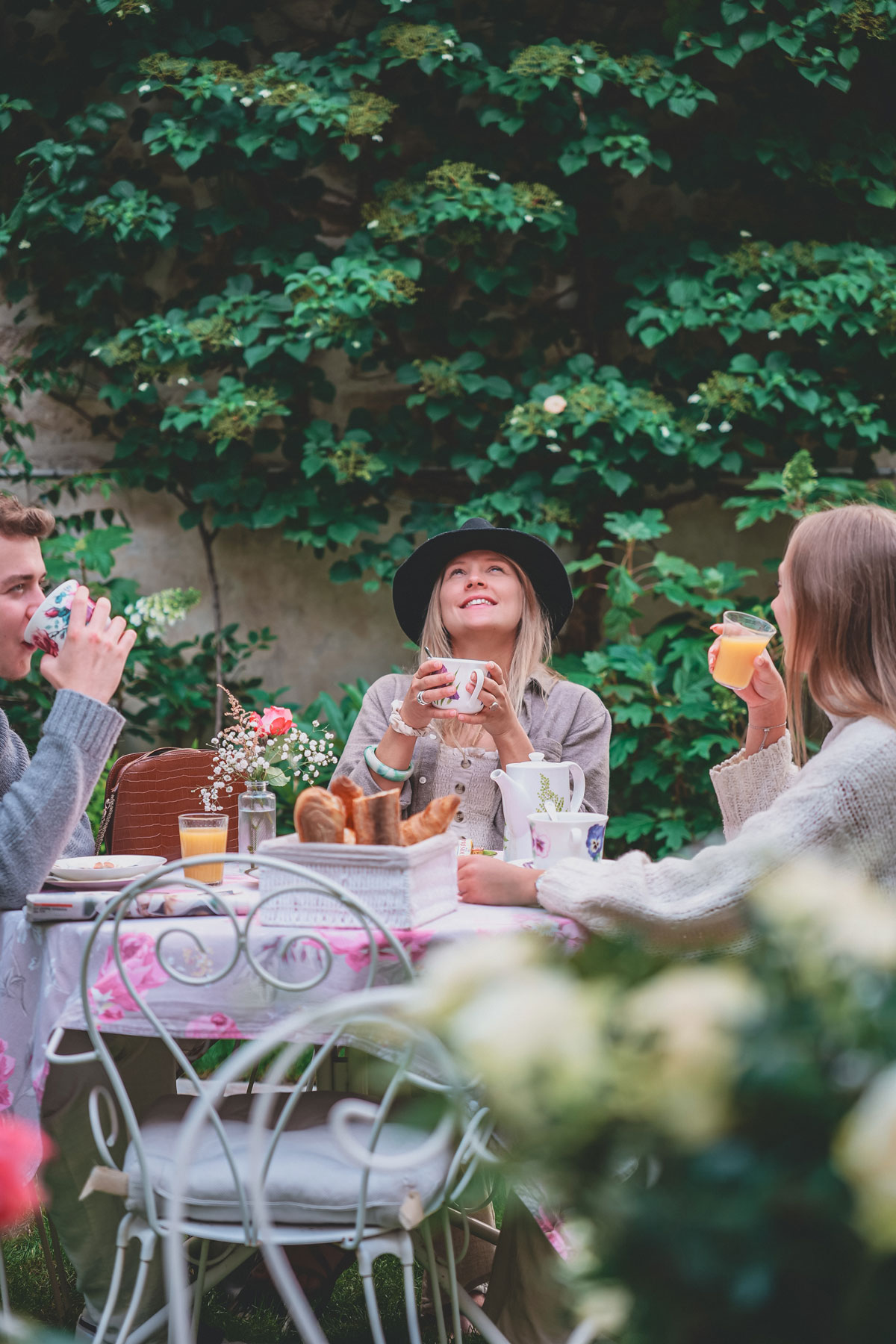 Image d'un groupe d'amis qui prend le petit déjeuner dans le jardin au petit matin.